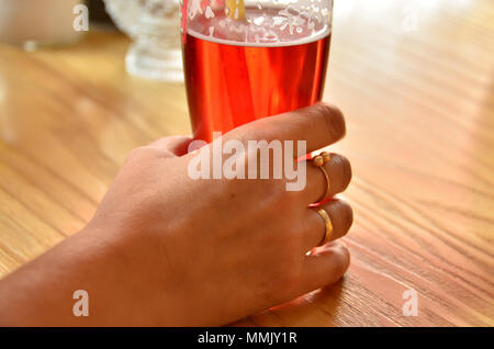 Weibliche hand mit einem Glas Bier mit Saft auf dem Tisch gemischt Stockfoto