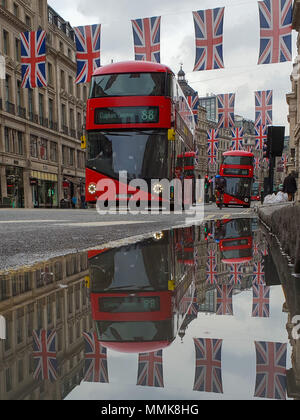 London. Vereinigtes Königreich 12. Mai 2018 - Reflexion der Union Fahnen und Busse in eine Pfütze von Regenwasser. Union Flag hängt über der London Regent Street vor der königlichen Hochzeit von Prinz Harry und Meghan Markle am 19. Mai in St. George's Chapel in Windsor Castle. Kredit Roamwithrakhee/Alamy leben Nachrichten Stockfoto