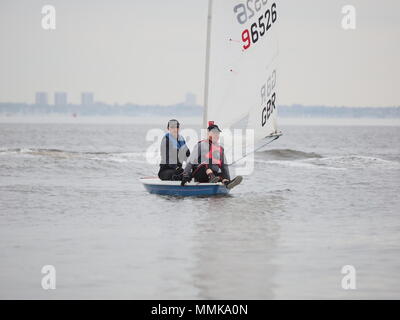 Sheerness, Kent, Großbritannien. 12. Mai 2018. UK Wetter: Nach einem hellen Anfang und leichtem Wind, Wolken und Regen hat für den Tag der offenen Tür in der Isle of Sheppey Sailing Club, Sheerness, Kent gerollt. Tag der offenen Tür ist Teil der nationalen der Royal Yachting Association' drücken, um das Boot' Initiative, die Segeln Vereine über Großbritannien sieht offen halten Tage Einsteiger in den Segelsport im Mai vorstellen. Pic: ein Mann nimmt eine Fahrt auf dem Bug eines Laser Klasse Jolle. Credit: James Bell/Alamy leben Nachrichten Stockfoto