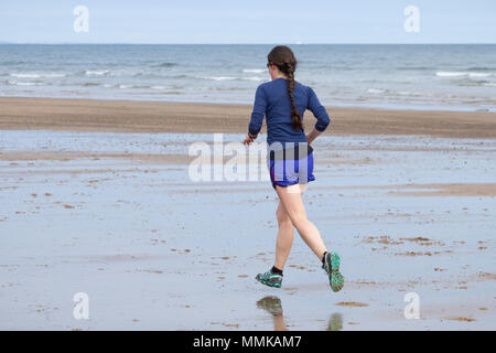 Junge Frau beim Joggen am Strand. Großbritannien Stockfoto