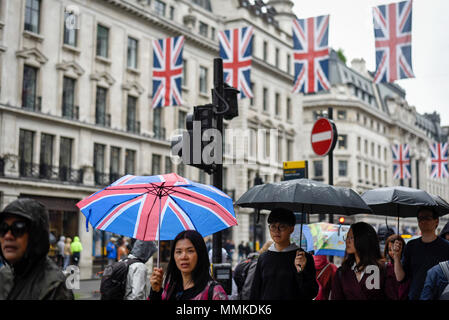 London, Großbritannien. 12. Mai 2018. UK Wetter - Touristische trägt einen Regenschirm mit der Union als Union Flag Flaggen oben schmücken die Regent Street vor der königlichen Hochzeit von Prinz Harry und Meghan Markle findet am 19. Mai 2018 eingerichtet. Credit: Stephen Chung/Alamy leben Nachrichten Stockfoto