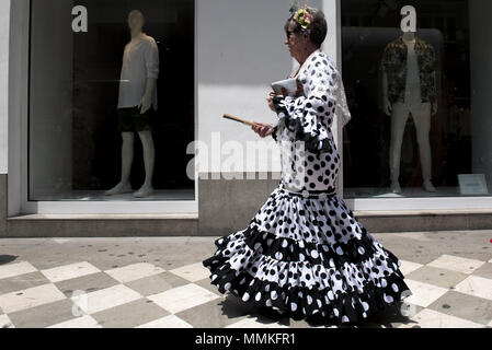 Granada, Granada, Spanien. 12. Mai 2018. Eine Frau tragen typische Kleid Pass vor einem Schaufenster während der Prozession von El Rocio. Die "Romeria del Rocio'' ist eines der beliebtesten Feste in Andalusien, Tausende von Pilgern in Almonte Dorf gehen (Huelva) anzubeten, Virgen del Rocio. Credit: Carlos Gil/SOPA Images/ZUMA Draht/Alamy leben Nachrichten Stockfoto
