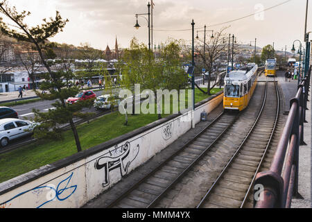 Budapest, Ungarn - 12. April 2018: Gelbe Straßenbahnen im Zentrum von Budapest, an sonnigen Tag. Berühmte Tram Nr. 2 Laufwerke von der Seite der Donau. Stockfoto