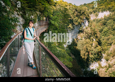 Zeda - gordi, Georgia. Schöne Frau posiert für Foto auf schmalen Hängebrücke oder Anhänger Straße bis zu 140 Meter über dem Abgrund auf dem Gebiet Okatse Stockfoto