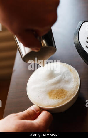 Man gießt in eine Tasse Kaffee mit Milch. Stockfoto