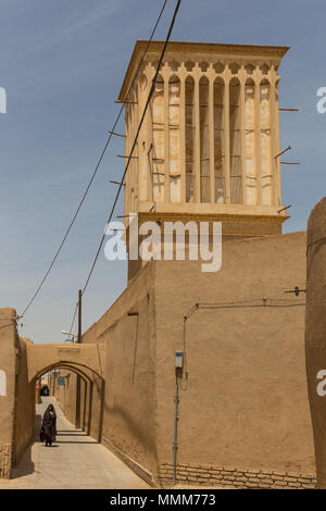 YAZD, IRAN - 27. APRIL 2015: Eine nicht identifizierte Frau geht durch die engen Straßen von Yazd im Iran Stockfoto