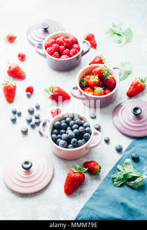 Sommer Obst Hintergrund, Blick von oben auf die Beeren, smoothie Zutaten, in Keramik farbige Cocotte, Heidelbeeren, Erdbeeren, Himbeeren, flach Stockfoto