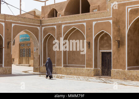 YAZD, IRAN - 27. APRIL 2015: Eine nicht identifizierte Frau geht durch die Straßen von Yazd im Iran Stockfoto