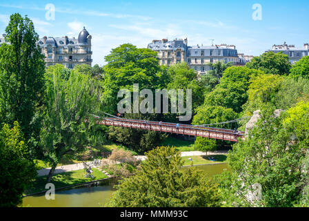 Eine Brücke im Parc des Buttes Chaumont mit Pariser Haussmann Architektur, Paris, Frankreich Stockfoto