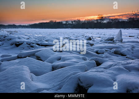 Eine schöne schneereiche Winter sunrise entlang der gefrorenen Maumee River im Nordwesten von Ohio. Riesige Klumpen von gebrochenem Eis wurde am Ufer des ri geschoben Stockfoto