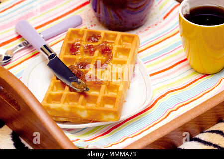 Nahaufnahme einer Waffel und ein Messer, Verbreitung die Marmelade, Tee im Hintergrund Stockfoto