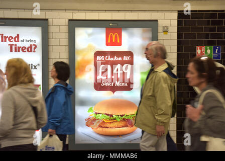 Menschen gehen vorbei Werbetafeln Förderung McDonalds BBQ Chicken Burger in der Notting Hill U-Bahn Station im Zentrum von London. Junk Food ad Stockfoto