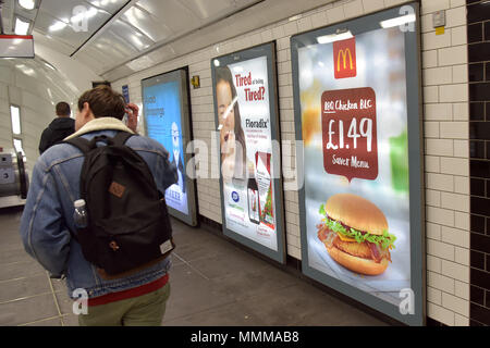 Menschen gehen vorbei Werbetafeln Förderung McDonalds BBQ Chicken Burger in der Notting Hill U-Bahn Station im Zentrum von London. Junk Food ad Stockfoto