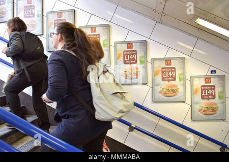 Menschen gehen vorbei Werbetafeln Förderung McDonalds BBQ Chicken Burger in der U-Bahn Station Oxford Circus in London. Junk Food ein Stockfoto