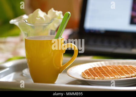 Runde Waffeln und Kaffee, Frühstück auf dem Hintergrund der Laptop Stockfoto