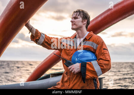 Deck Officer an Deck von offshore Schiff oder auf dem Schiff, das Tragen von PSA Persönliche Schutzausrüstung. Er hält VHF walkie-talkie Radio in den Händen. Traum arbeiten an Stockfoto