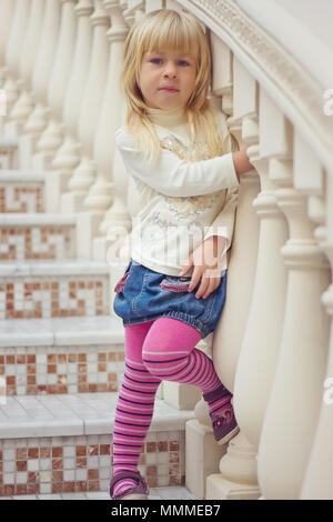Mädchen 3 Jahre alt in einer Jeans Rock und rosa Strumpfhose ist eine schöne Treppe Stockfoto