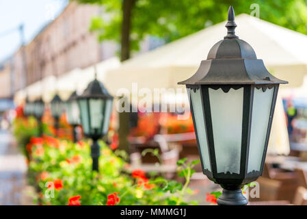 Stilvolle retro Laterne in der Stadt in der Nähe von schönen Blumen umgeben - oben Stockfoto