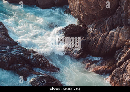 Meer Wellen gegen die Felsen in der Abendsonne Stockfoto