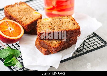 Scheiben von Blut orange vegetarische Pound Cake auf einem Rack. Weißer Stein Hintergrund. Stockfoto