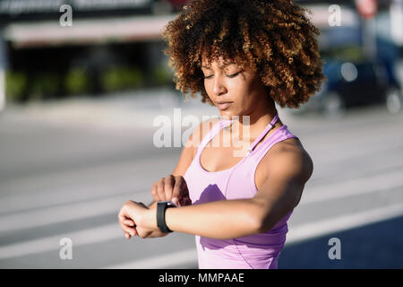 Junge schwarze Frau mit smartwatch berühren Touchscreen im Active Sports Activity. Mädchen mit afro Haar ihr smart Watch. Stockfoto