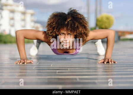 Schwarz passende Frau pushups auf städtischen Boden. Junge Frauen, die auf der Straße arbeiten. Stockfoto