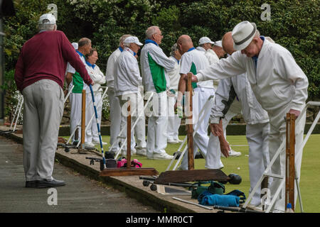 Viele ältere oder älter pensionierten Herren bowling Gekleidet in weiße Kleidung zu Bowls Club treffen auf der Isle of Wight in Newport Seaclose Park. Stockfoto