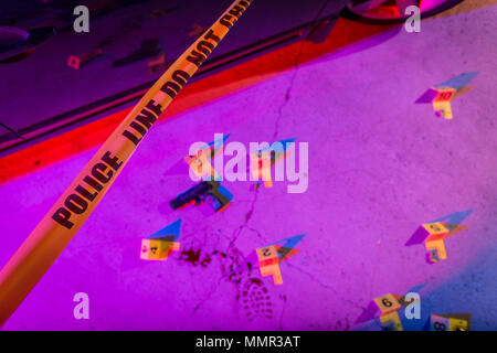 Eine schwarze Pistole legt auf dem Bürgersteig in einem Tatort, mit einem Marker gekennzeichnet. Stockfoto