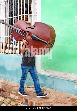 Trinidad, Kuba, 26. November 2017 - Der Mensch geht hinunter die Straße mit seinem Cello auf seiner Schulter Stockfoto