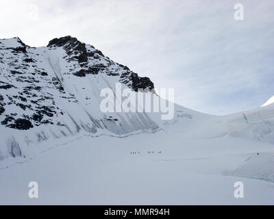 Eine Gruppe von tourengängern Wandern entlang einer steilen Nordwand und hochalpinen Gipfel auf dem Weg nach oben auf einer Skitour in den Alpen in der Nähe von Zermatt Stockfoto