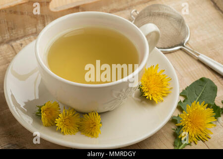 Tasse frischen gesunden Löwenzahntee geschmückt mit Blumen Stockfoto