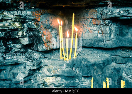Wachs Kirche Kerzen in Rock Nischen. Heiliger Ort. Stockfoto