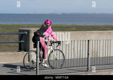 Mollige Frau, die in leuchtendem rosa Outfit in Southport, Merseyside, Großbritannien, radelt 13/05/2018. Wetter in Großbritannien. Sonniger Tag an der Küste, da die Temperaturen im Nordwesten voraussichtlich steigen werden. Zu Beginn des Tages können die Bewohner des Resorts an der Strandpromenade leichte Morgenübungen machen. Quelle: MediaWorldImages/AlamyLiveNews Stockfoto