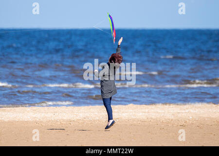 Southport, Merseyside. 13. Mai 2018. UK Wetter. Eine Frau hat viel Spaß gemacht, die versuchen, ihre Drachen am goldenen Sandstrand von Southport Strand in Merseyside zu fangen. Credit: cernan Elias/Alamy leben Nachrichten Stockfoto