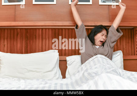 Junge Frau strecken und Gähnen im Bett nach dem Aufwachen. Morgen und Erwachen Stockfoto