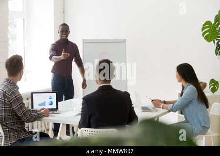 Freundlich lächelnd afrikanischen Trainer im Gespräch mit Geschäftsleuten, Stockfoto