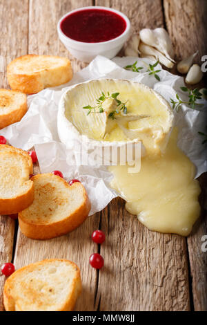 Französische geschmolzener Camembert mit Toast und Preiselbeersoße close-up auf dem Tisch. Vertikal, rustikalen Stil Stockfoto