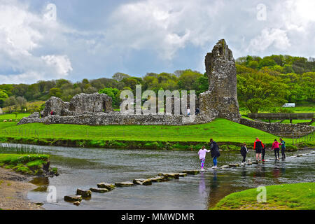 Eine erweiterte Familie Gruppe (plus Hund!) Viel Spaß beim Überqueren der Trittsteine über den Fluss, wie es vergeht Ewenny Ogmore Castle in der Nähe von Bridgend, South Wales Stockfoto