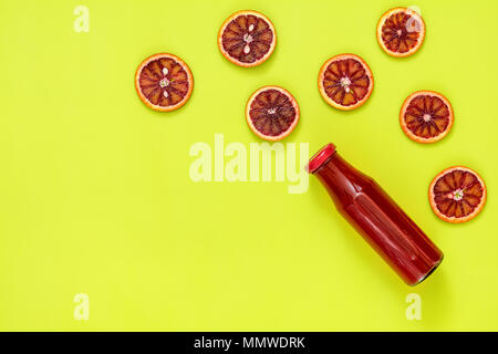 Schönes essen Kunst Hintergrund. Roten Saft in Flaschen geschnitten Blut orange Frucht auf helle grüne Fläche. Stockfoto