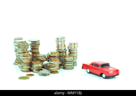 Geld Münzen und rote Spielzeugauto auf weißem Hintergrund gestapelt Stockfoto
