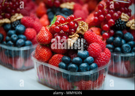 Bunte Früchte und Beeren für den Verkauf in einem offenen Markt. Reife rote Johannisbeeren, Himbeeren, Heidelbeeren, Brombeeren und Walnüsse. Stockfoto