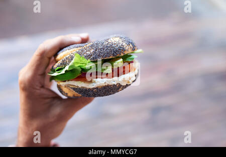 Mann mit einem leckeren Frischkäse und Lachs Bagel Stockfoto