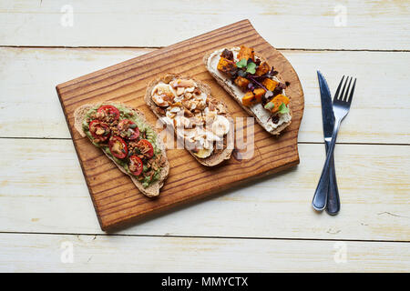Leckere Sandwiches geöffnet gegenüber sitzen mit Besteck auf dem Tisch Stockfoto