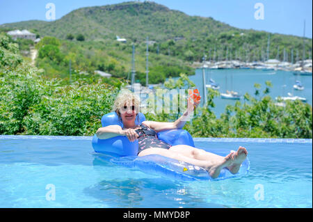 Antigua Inseln der Kleinen Antillen in der Karibik West Indies - Frau auf aufblasbaren in einem Infinity-Pool mit Blick auf English Harbour Stockfoto