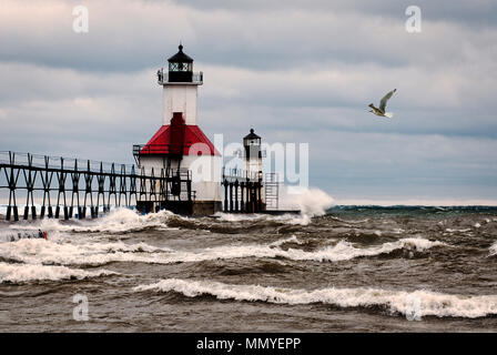 Einen kleinen Leuchtturm auf einem Pier in St. Joeseph Michigan während stromy Wetter mit Wellen, die in die Pier und einen seagulll fliegen durch. Stockfoto