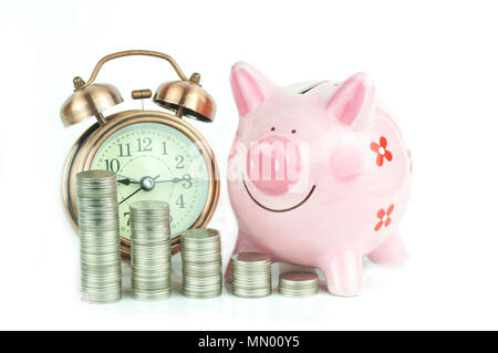 Der Münzen gestapelt, rosa Sparschwein und Wecker auf weißem Hintergrund, Konzept für Wachstum, Sparen und Investitionen in Unternehmen Stockfoto