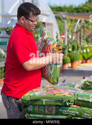 Garten Center Personal stapeln Taschen von Kompost für den Verkauf in einem Gewächshaus Stockfoto