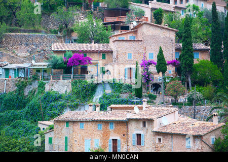 Mallorca Deia Blick auf das Dorf mit rosa Bougainvilleen, grüne Gärten und traditionelle und typische honigfarbenen Trockenmauern Gebäude. Stockfoto