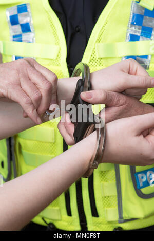 Polizeioffizier Entriegelung Handschellen aus eines verdächtigen Handgelenke Stockfoto