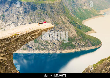 Sportliche Frau posiert auf Trolltunga. Glückliche Wanderer genießen die schönen See und gutes Wetter in Norwegen. Stockfoto